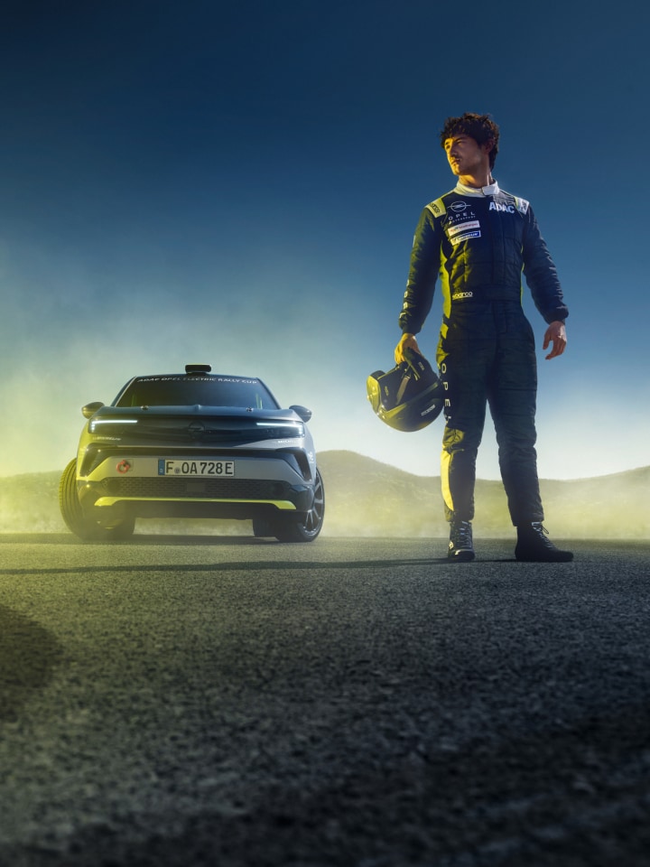 Vista anteriore di un Mokka GSE Rally con accanto un pilota Rally con il casco in mano