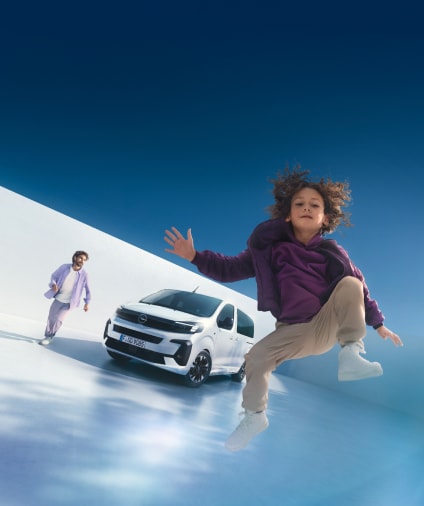 Un bambino che salta e si diverte davanti a un veicolo Opel bianco fermo