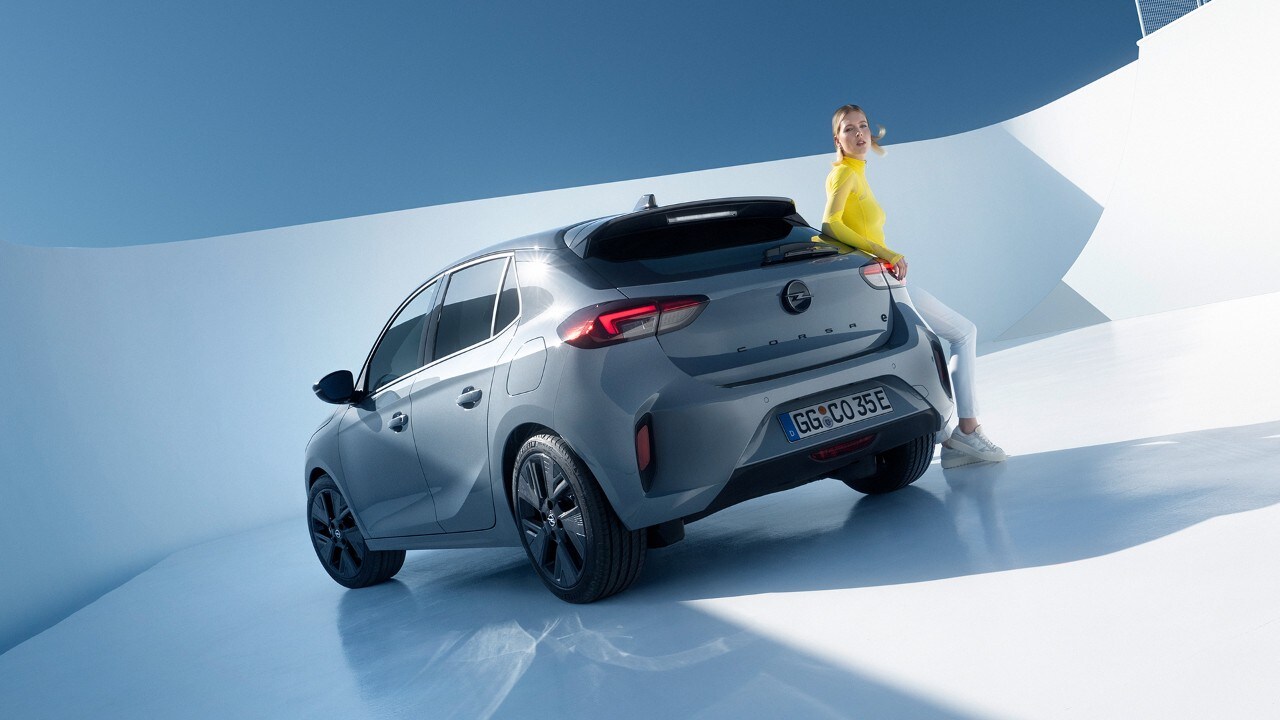 Vista laterale posteriore di Opel Corsa Electric grigia con cerchi in lega e tetto neri