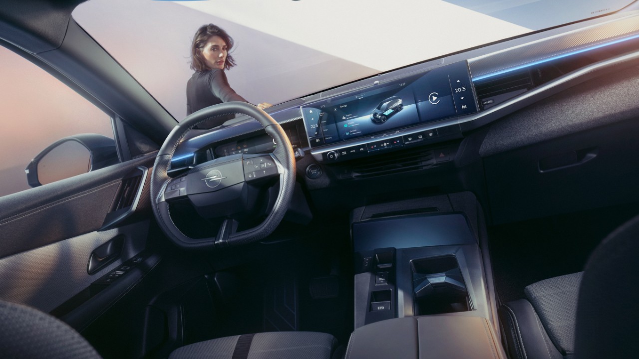 Vista ravvicinata del display pure panel di Opel Grandland con una donna appoggiata all'auto e che guarda all'interno